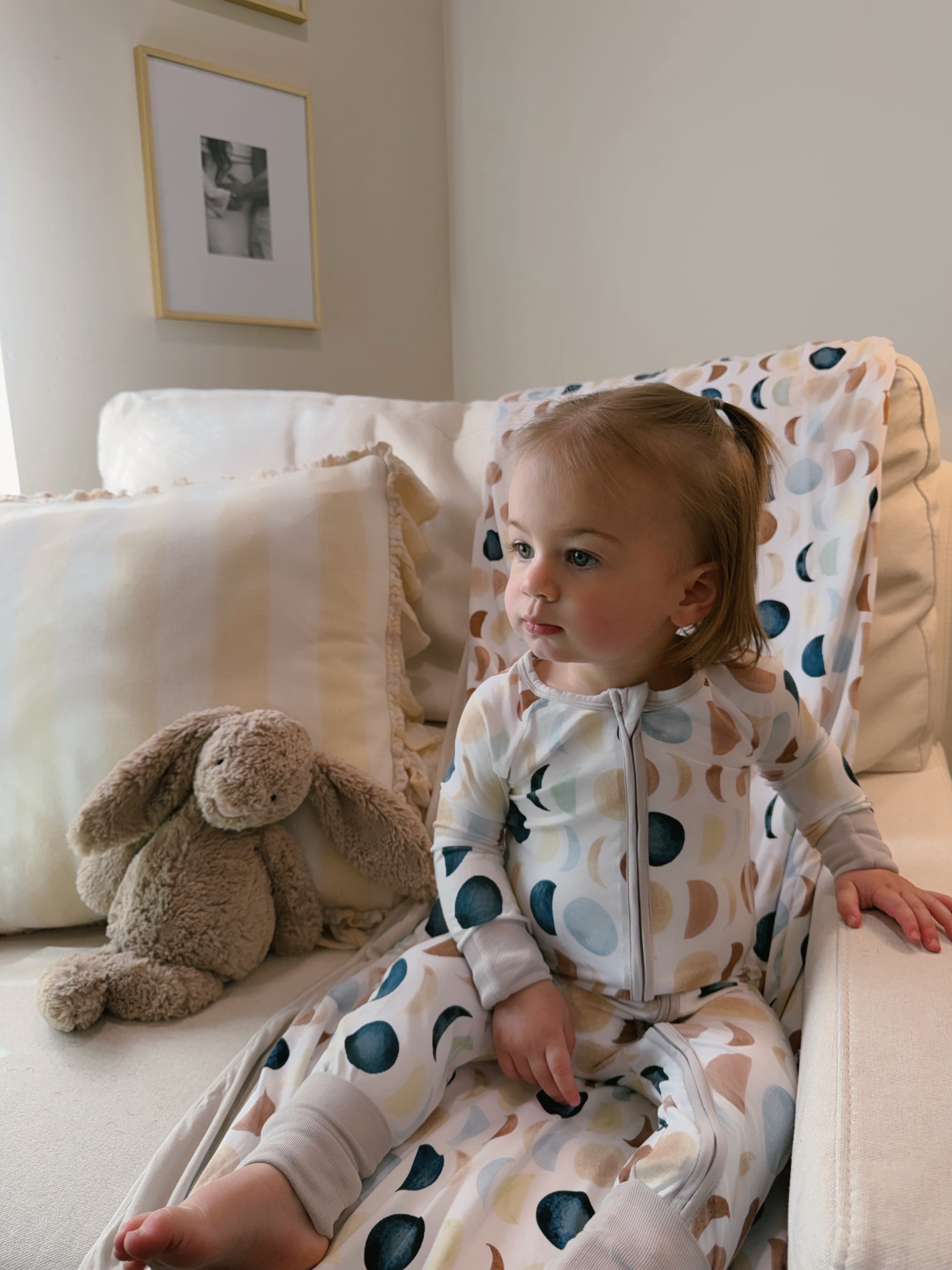 Child sitting on a chair, wearing a Luna Neutral Zippy