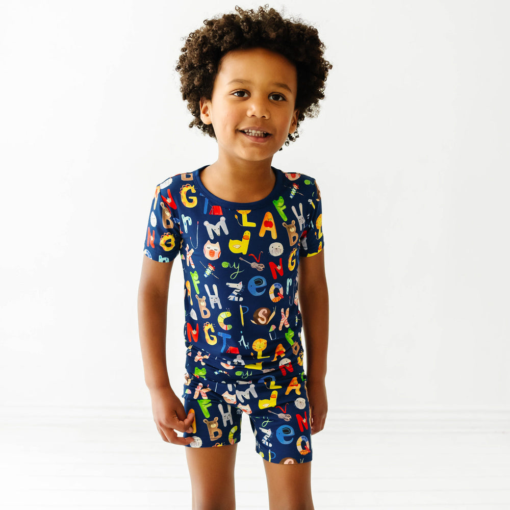 Child wearing a Navy Alphabet Friends two piece short sleeve and shorts pajama set