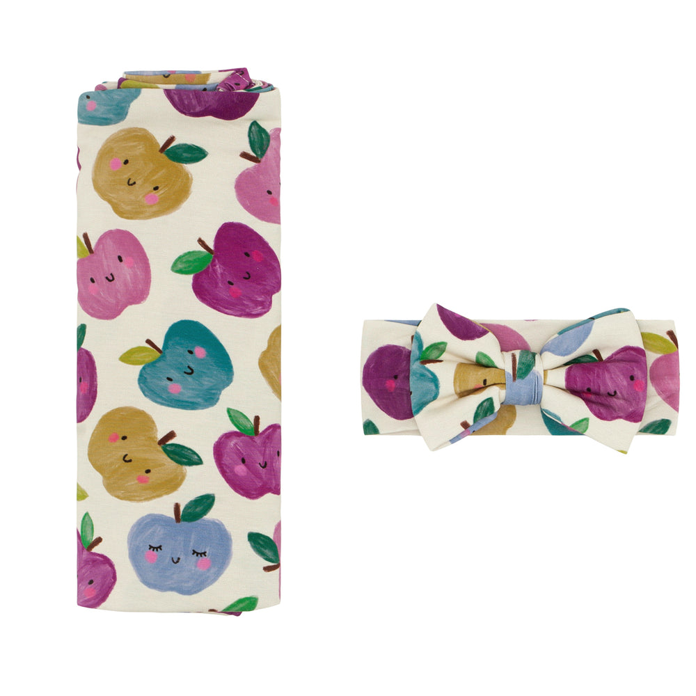 Flat lay image of a Berry Apple of my Eye swaddle and luxe bow headband set