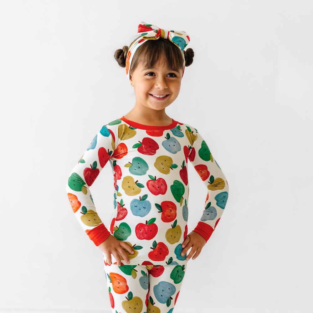 Child wearing a Red Apple of My Eye luxe bow headband and matching pajamas