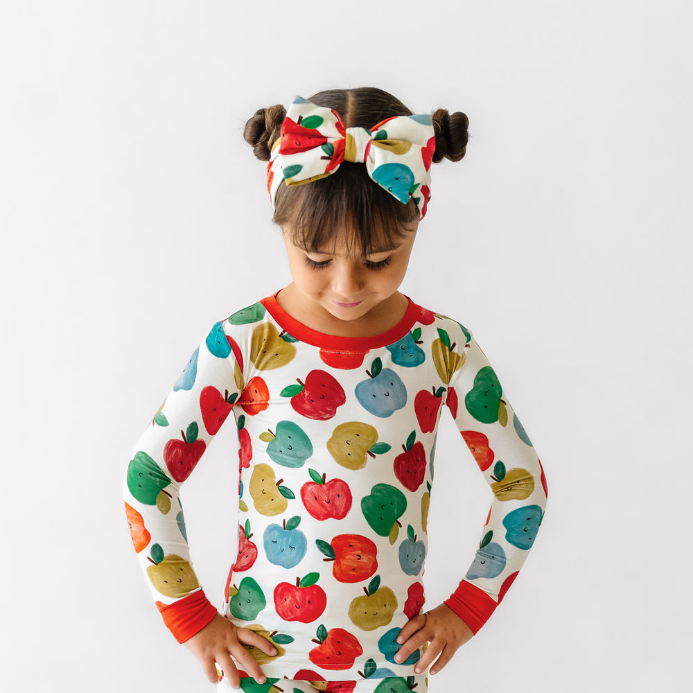 Child looking down wearing a Red Apple of My Eye luxe bow headband and matching pajamas