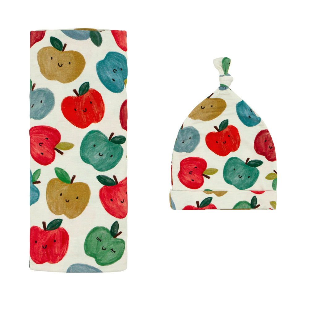 Flat lay image of a Red Apple of My Eye swaddle and hat set