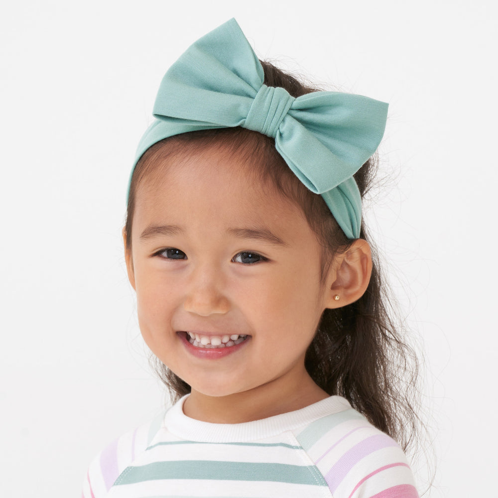 Close up image of a child wearing an Aqua Mist luxe bow headband