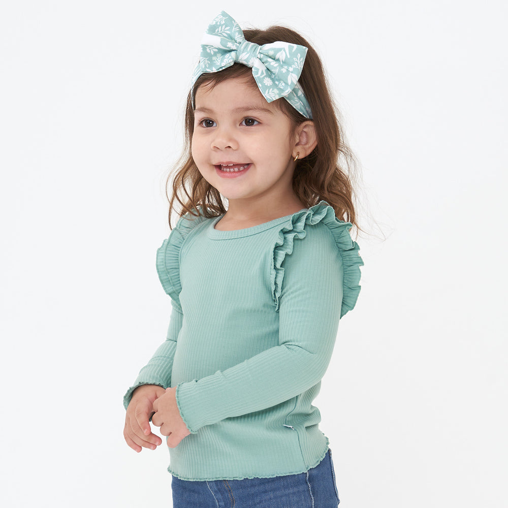 Child wearing a Aqua Mist Ribbed Flutter Lettuce Tee paired with a Unicorn Garden luxe bow headband