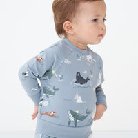 Side view close up image of a child wearing an Arctic Animals printed crewneck sweatshirt