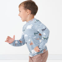 Close up side view image of a child wearing an Arctic Animals printed pocket tee and coordinating joggers