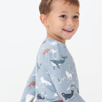 Close up side view image of a child wearing an Arctic Animals printed pocket tee
