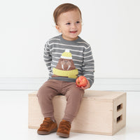 Child sitting on a box wearing a Walrus knit sweater and coordinating Light Cocoa joggers
