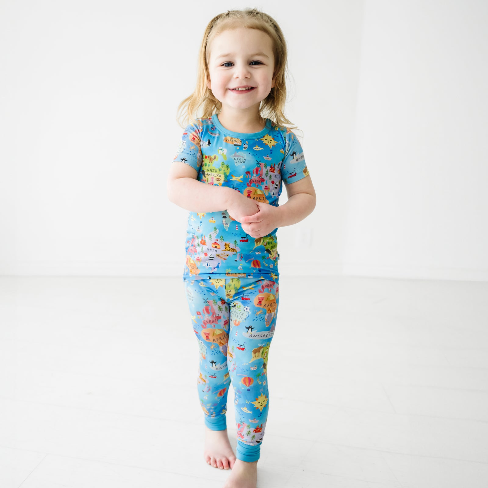 Child walking forward wearing an Around the World Two-Piece Short Sleeve Pajama Set