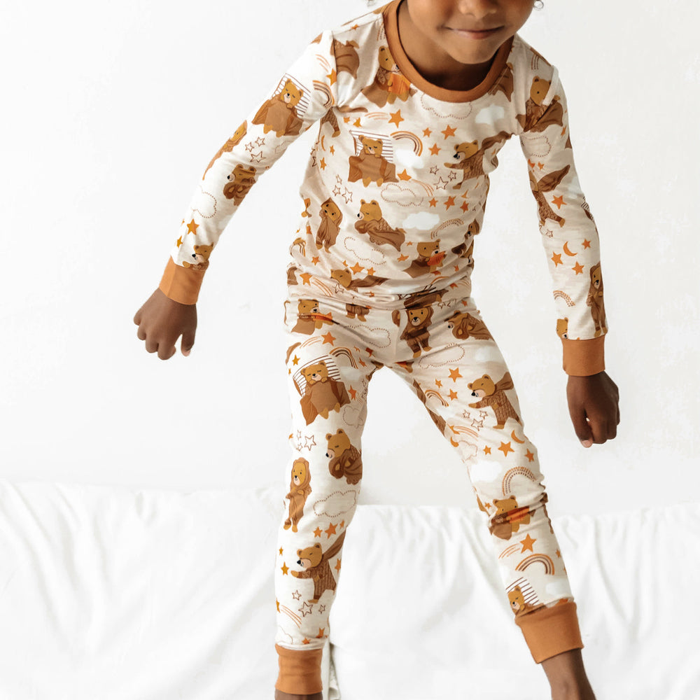 Close up of a child standing on a bed wearing a Beary Sleepy Two-Piece Pajama Set