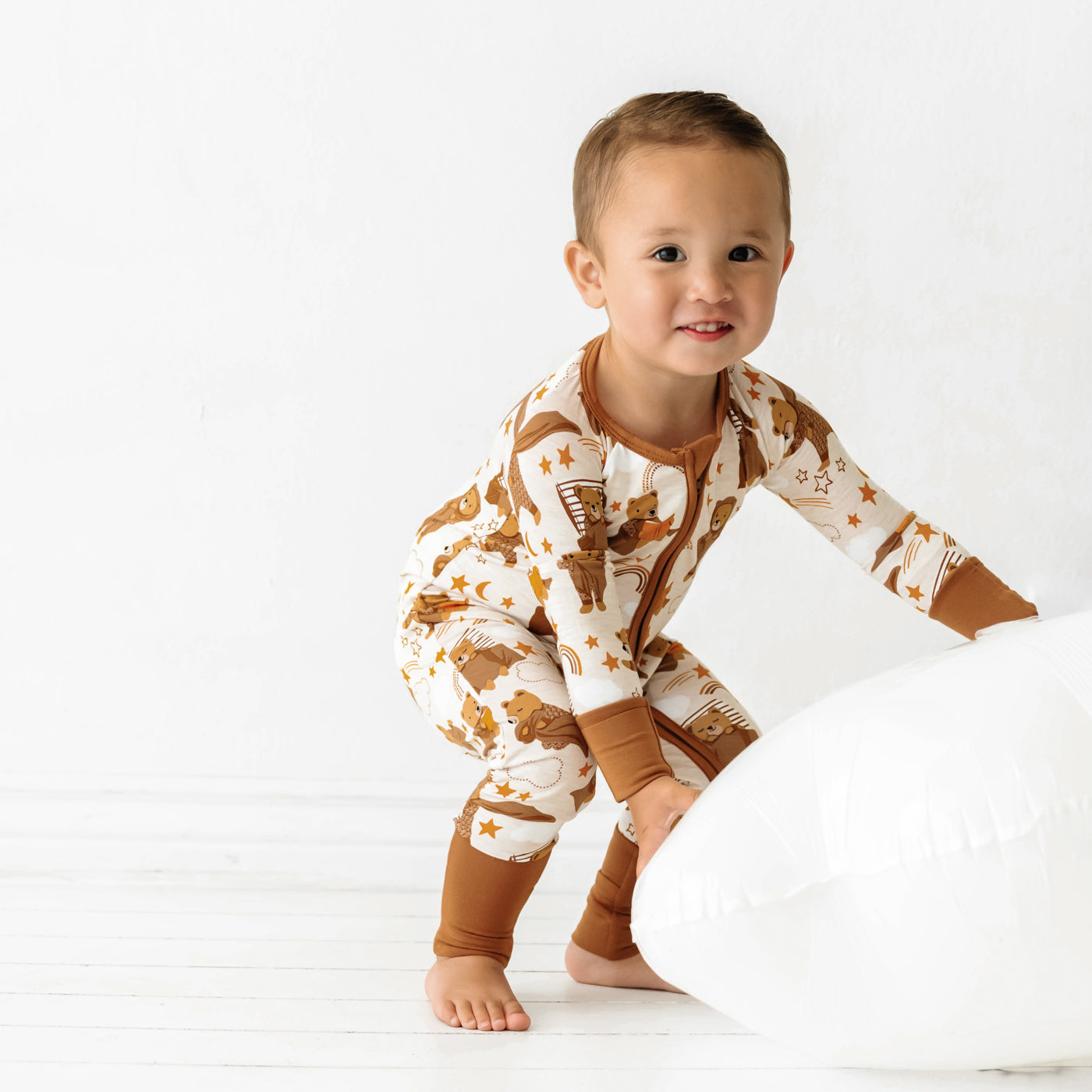 Child playing with a pillow and wearing a Beary Sleepy Zippy