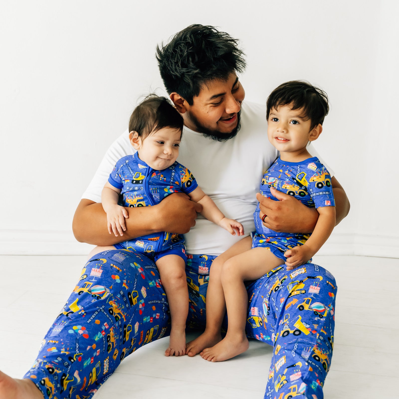 Father and two children wearing matching Birthday Builders pajamas