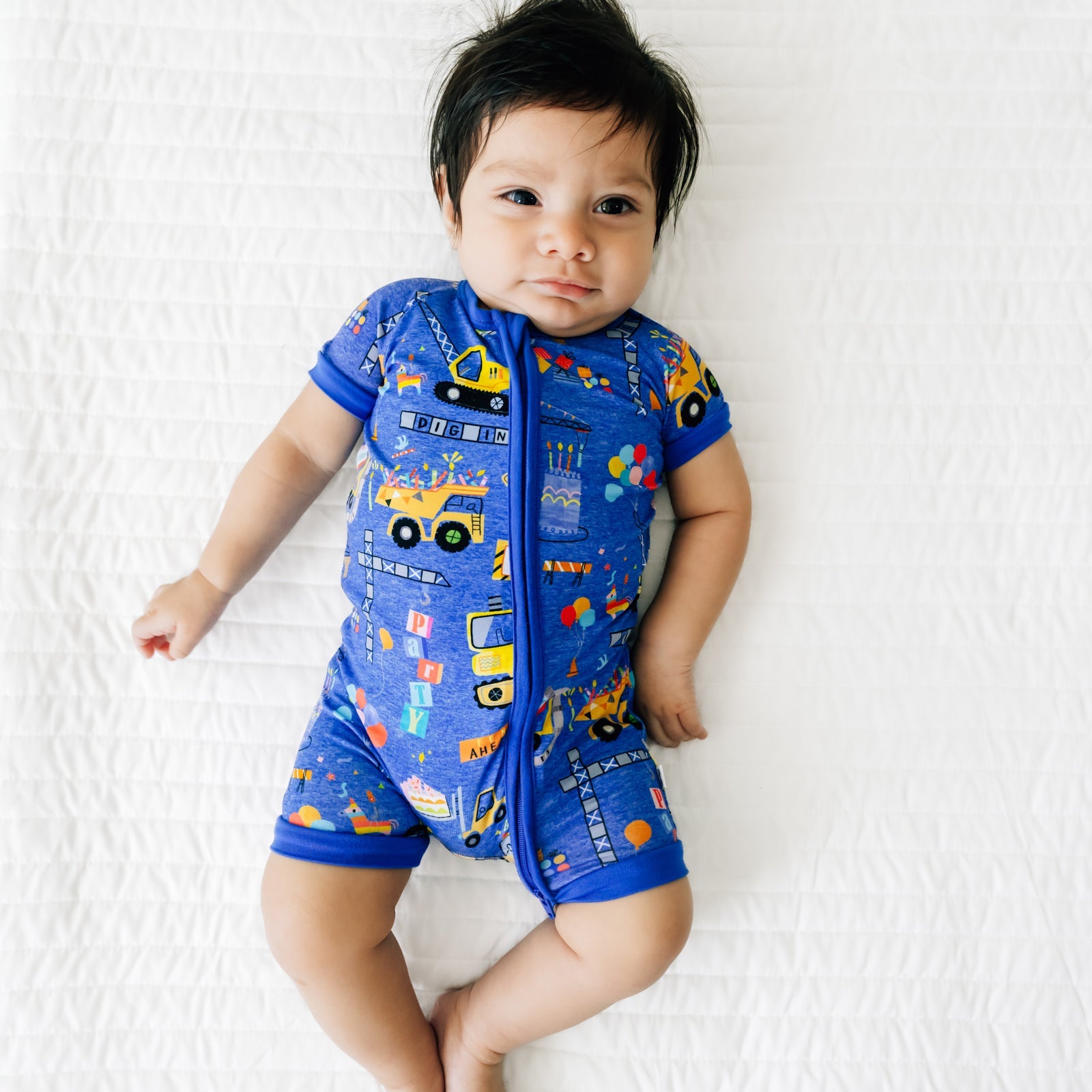 Baby lying down wearing a Birthday Builders Shorty Zippy