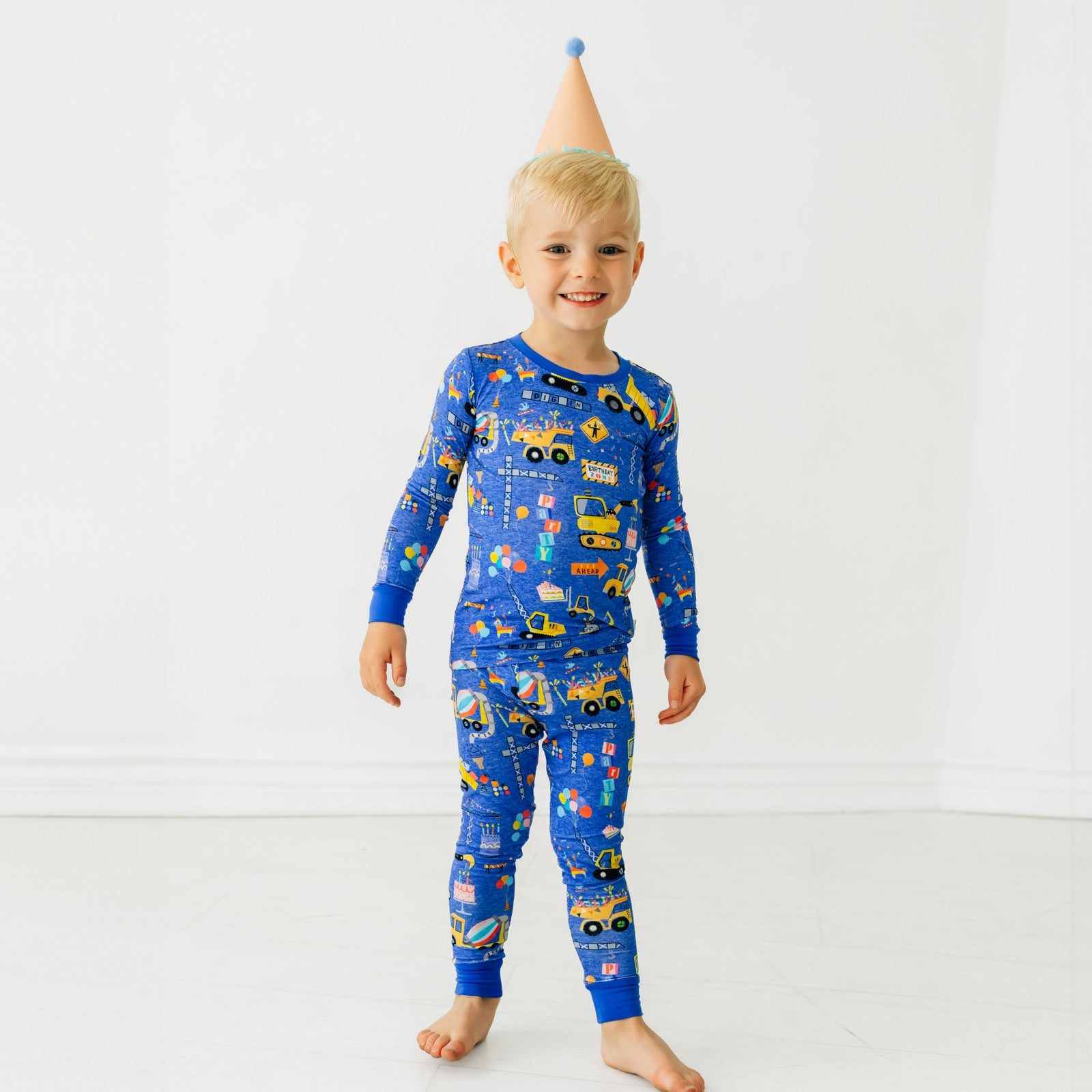 Child wearing a Birthday Builders Two-Piece Pajama Set with a party hat on their head
