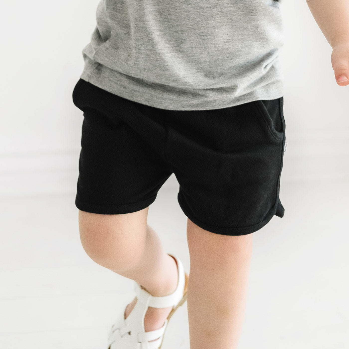 Close up of a child wearing Black Dolphin Shorts and coordinating light heather gray girls shirt