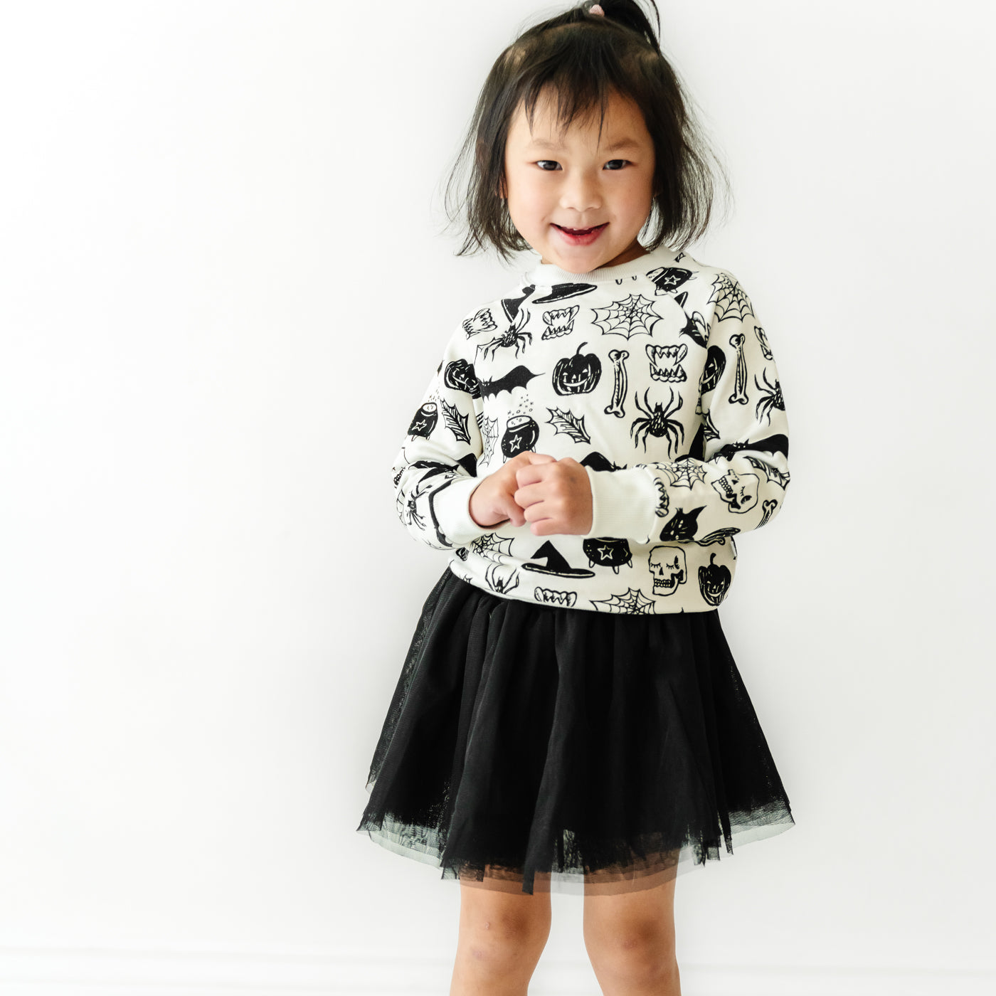 Child posing wearing a Witches Brew crewneck paired with a Black bamboo viscose lined tutu