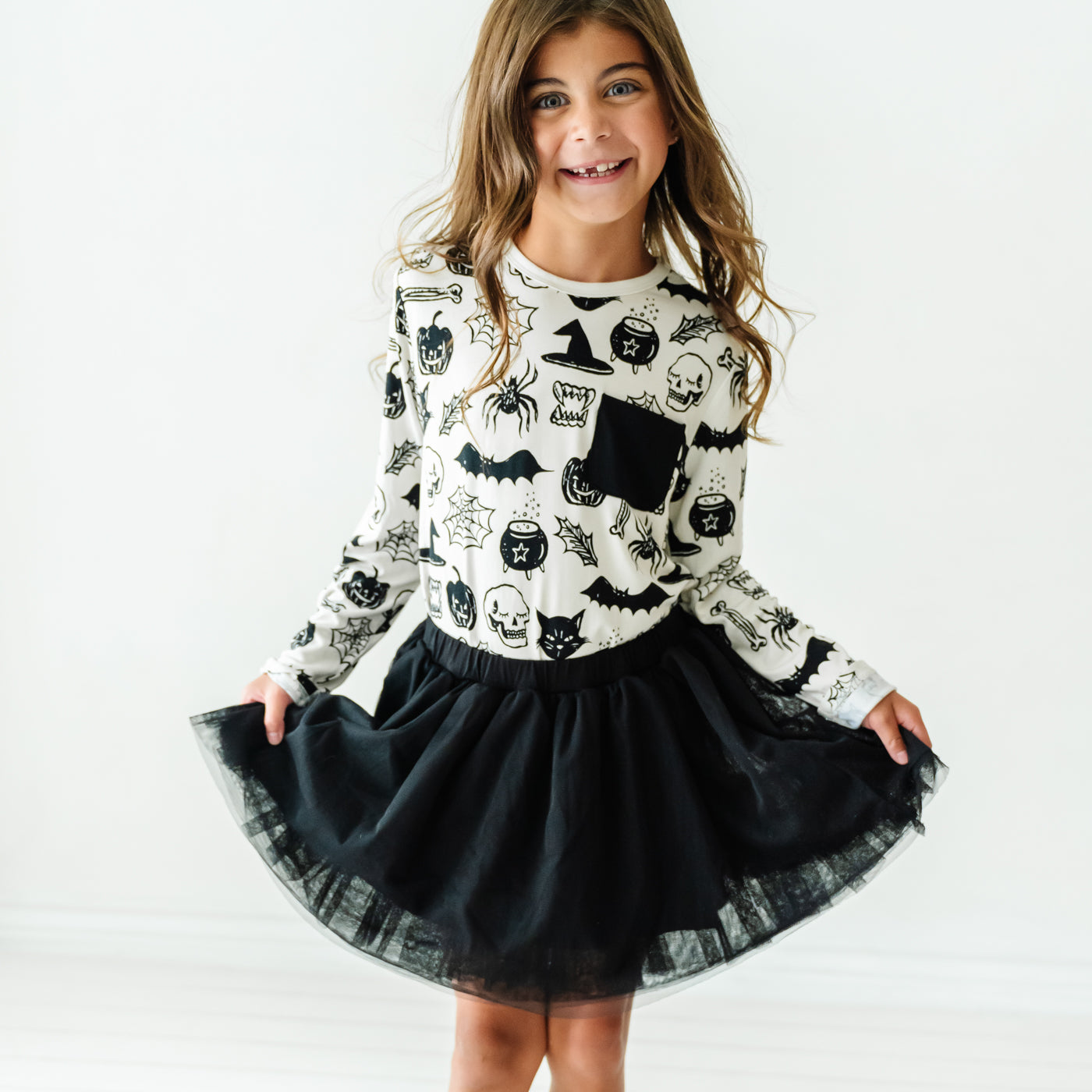 Child posing wearing a Witches Brew pocket tee paired with a Black bamboo viscose lined tutu