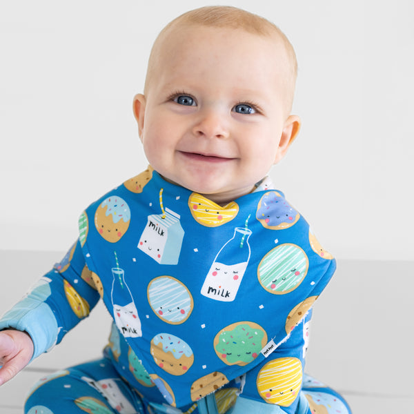 Close up of a child wearing a Blue Cookies & Milk baby boy bib over matching Blue Cookies & Milk bamboo pajamas