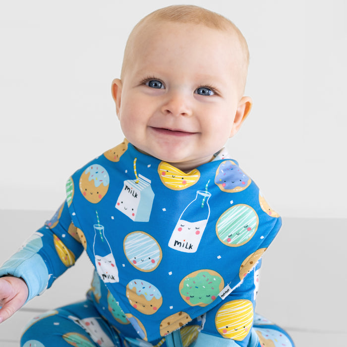 Close up of a child wearing a Blue Cookies & Milk baby boy bib over matching Blue Cookies & Milk bamboo pajamas