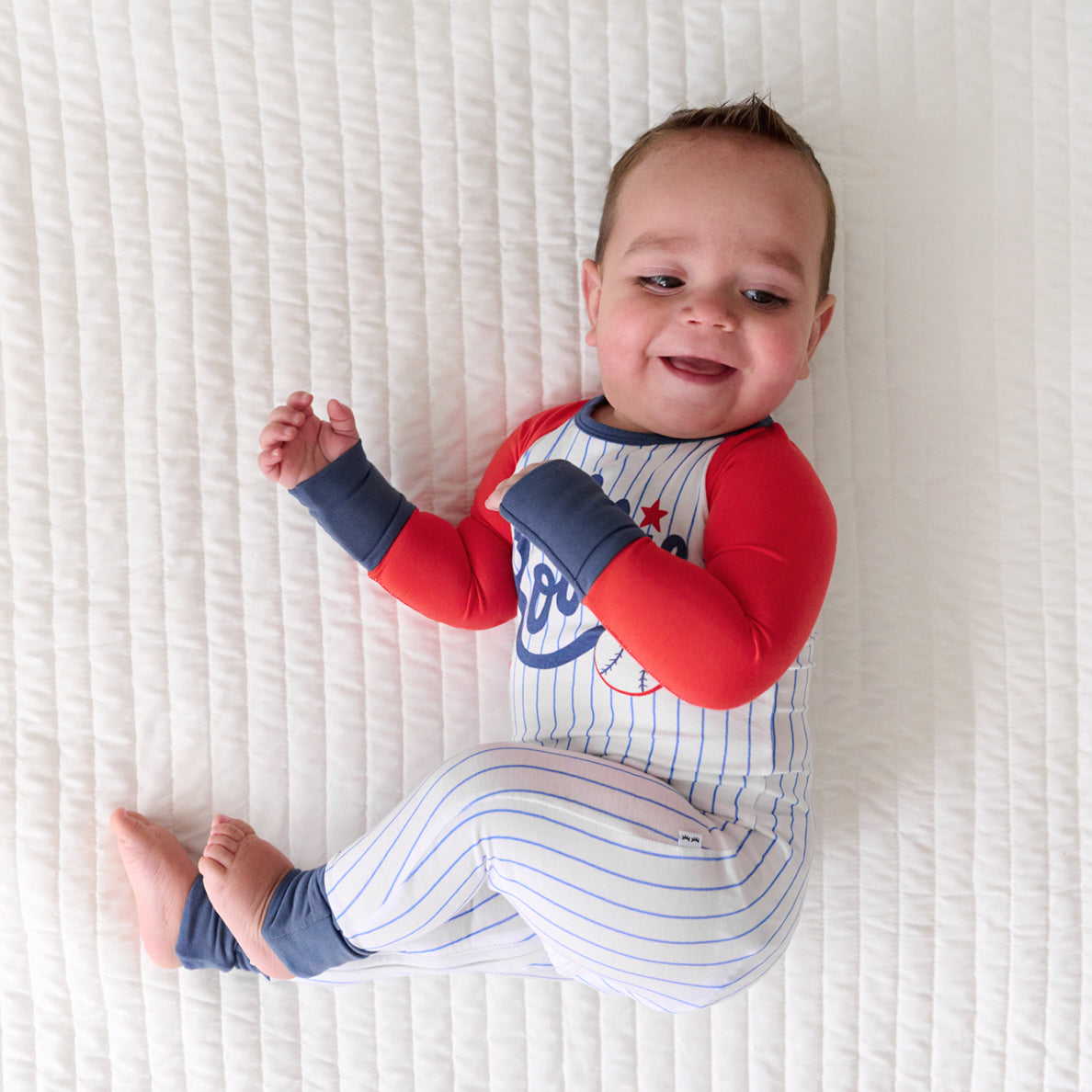 Child laying on a bed wearing a Blue Lil Rookie Crescent Zippy