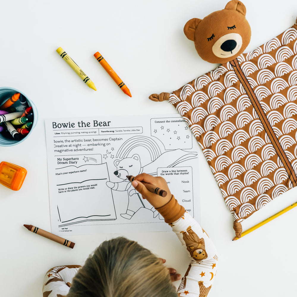 child working on a coloring page for Bowie the Bear with his Bowie the Bear Sleepyhead Lovey