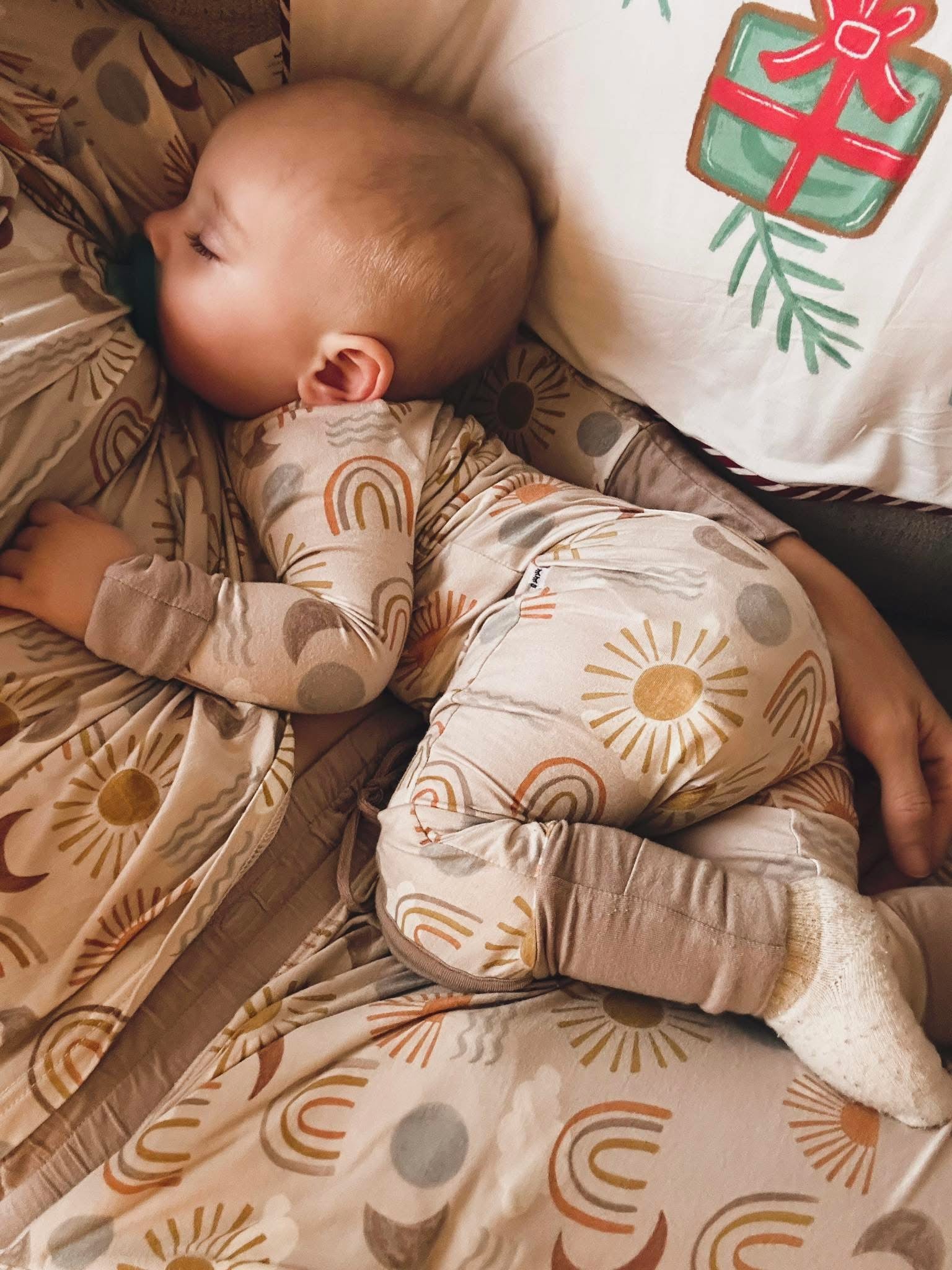 Infant being held by their mother, wearing a Desert Sunrise Zippy