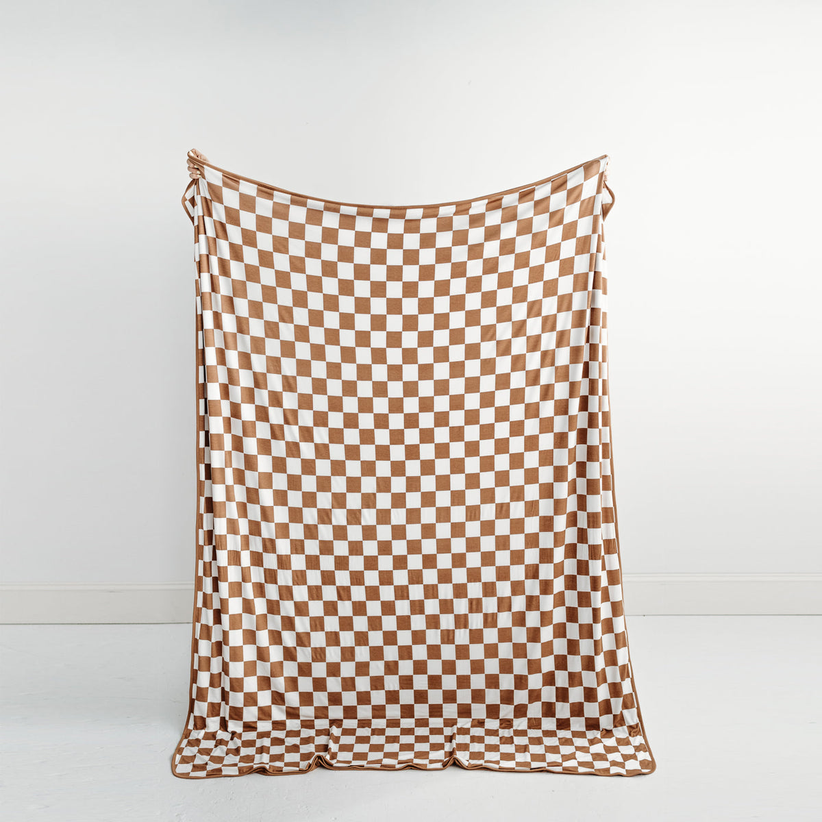 Adult holding up a Caramel Checks oversized bamboo blanket in front of them