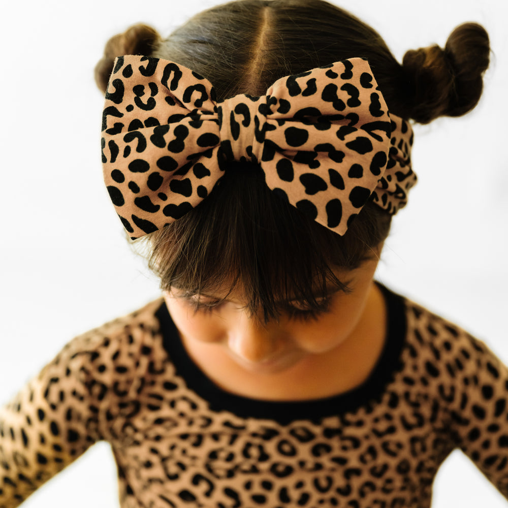 Child looking down wearing a Classic Leopard printed luxe bow headband and matching pajamas