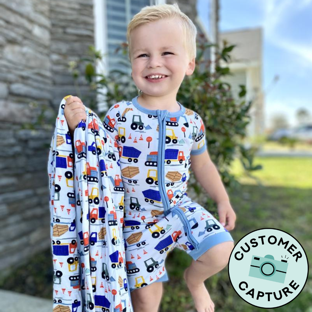 Customer Capture image of a child wearing a Construction Shorty Zippy holding a matching large cloud blanket