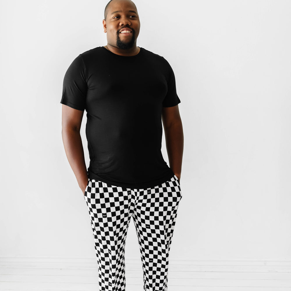Click to see full screen - Man wearing Cool Checks printed men's pajama bottoms paired with a solid black men's pajama top