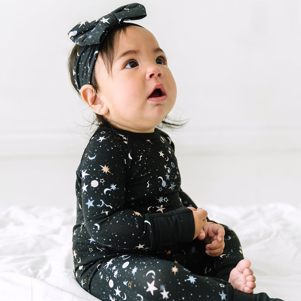 Child wearing a Counting Stars printed luxe bow headband and matching crescent zippy