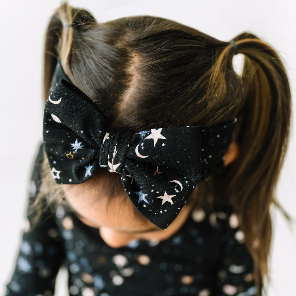 Close up image of a child wearing a Counting Stars printed luxe bow headband