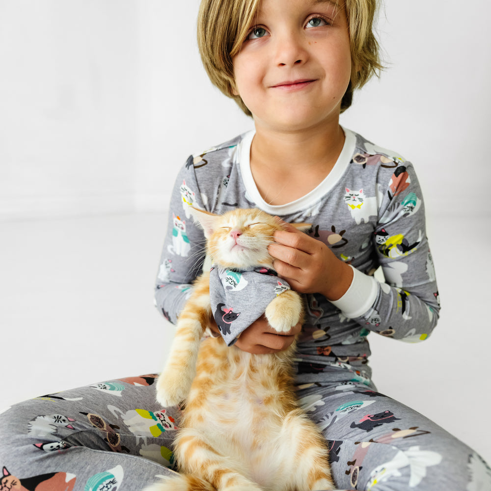 Child wearing a Cozy Cats two-piece pajama set with a cat wearing a matching pet bandana