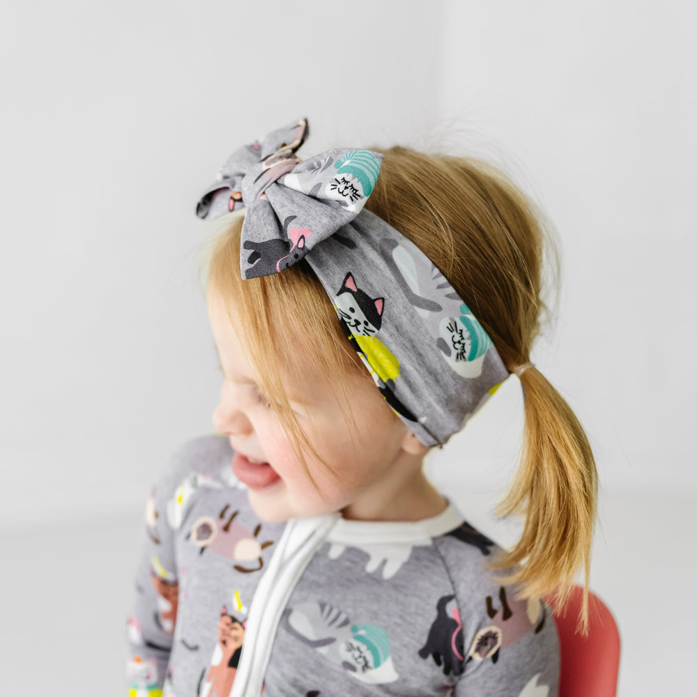 Side view image of a child wearing a Cozy Cats luxe bow headband and matching zippy
