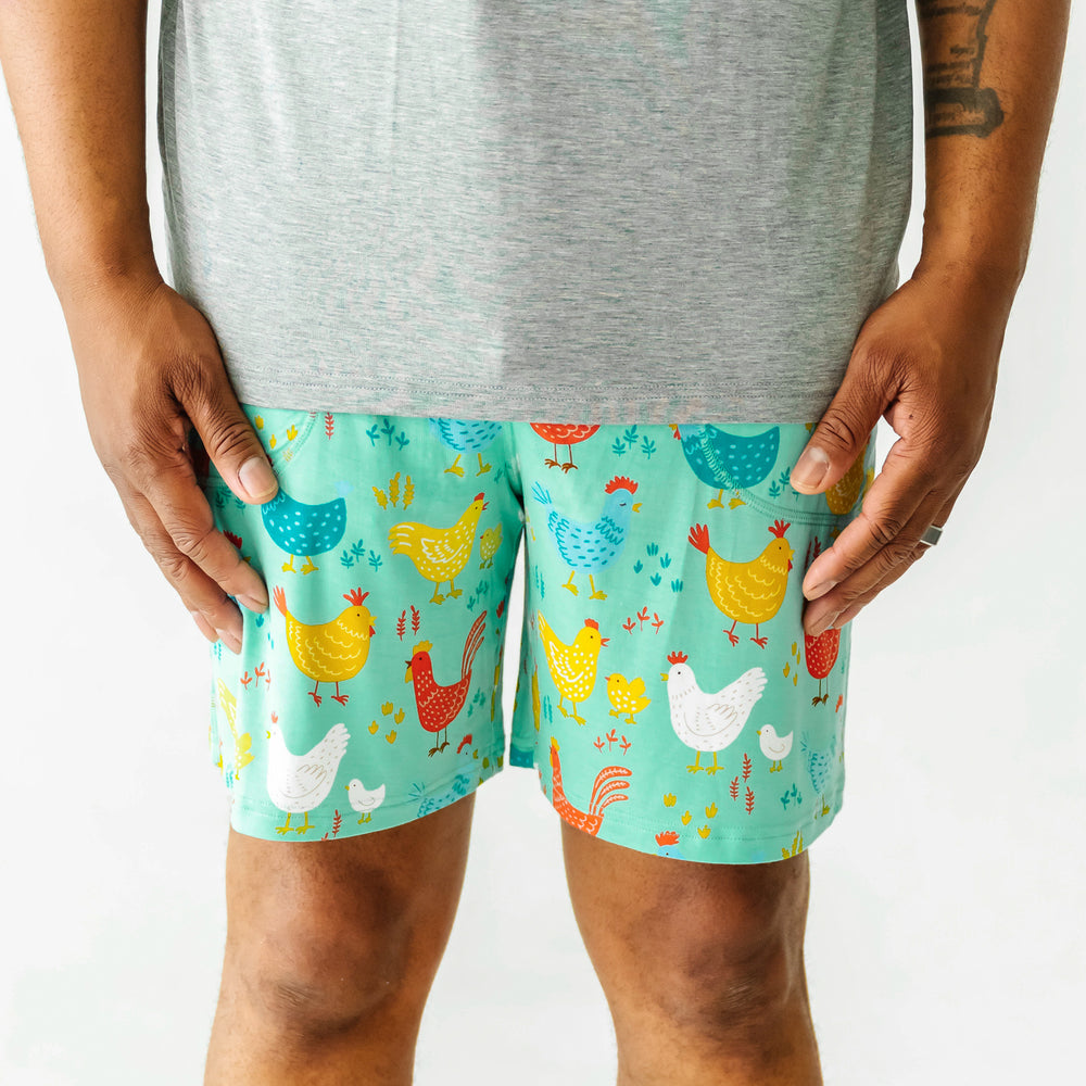 Close up image of a man wearing Cozy Coop printed men's pajama shorts paired with a men's Heather Gray pajama top 