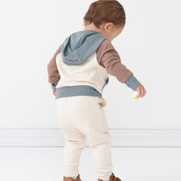 Back view of a child wearing a Colorblock pullover hoodie paired with Cream joggers