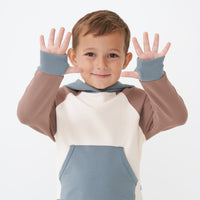 Close up image of a child wearing a Colorblock pullover hoodie showing off the thumb holes