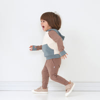 Alternate profile view of a child wearing a Colorblock pullover hoodie paired with Light Cocoa Joggers