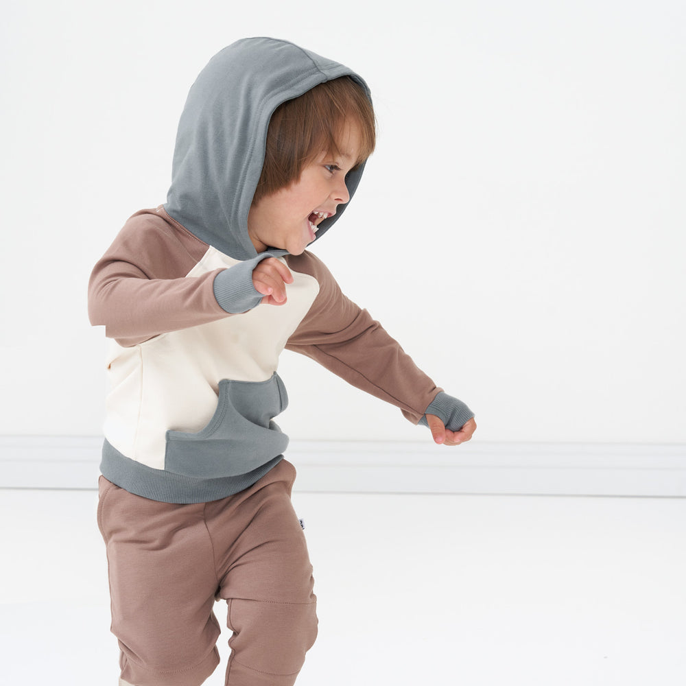 Profile view of a child wearing a Colorblock pullover hoodie paired with Light Cocoa Joggers