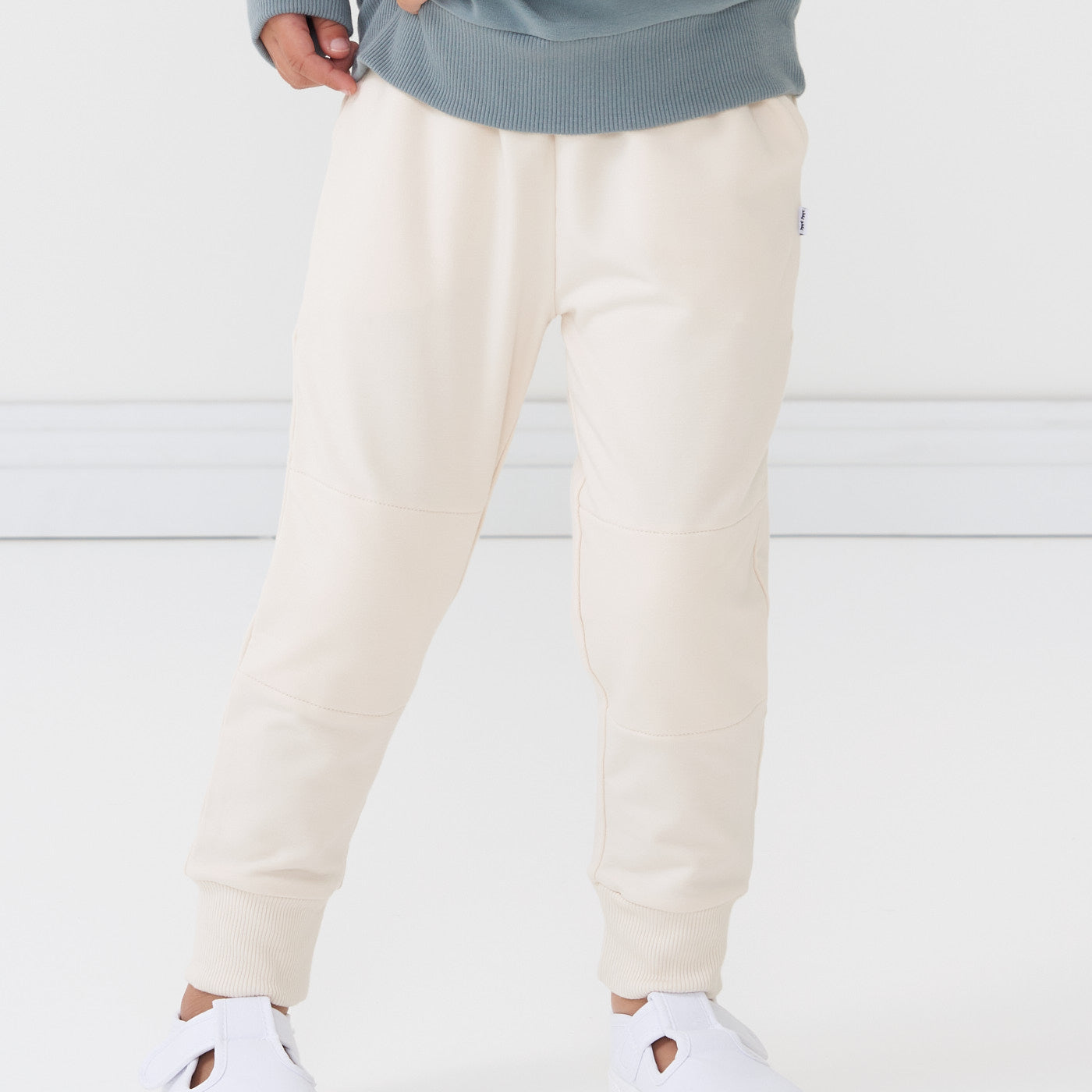 Close up image of a child wearing Cream joggers