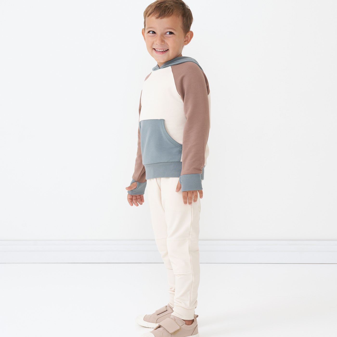 Side view image of a child wearing Cream joggers and coordinating Colorblock pullover hoodie