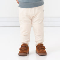 Close up image of a young child wearing Cream joggers