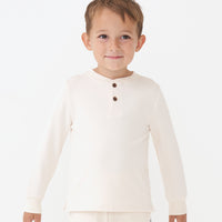 Close up image of a child wearing a Cream henley tee