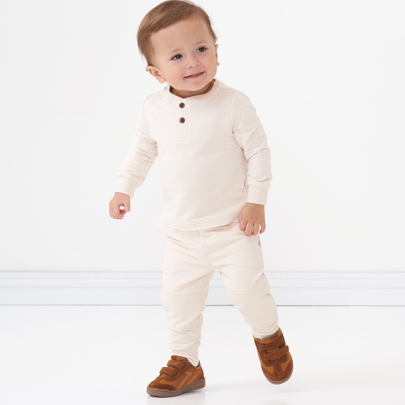 Child walking wearing a Cream henley tee and matching joggers