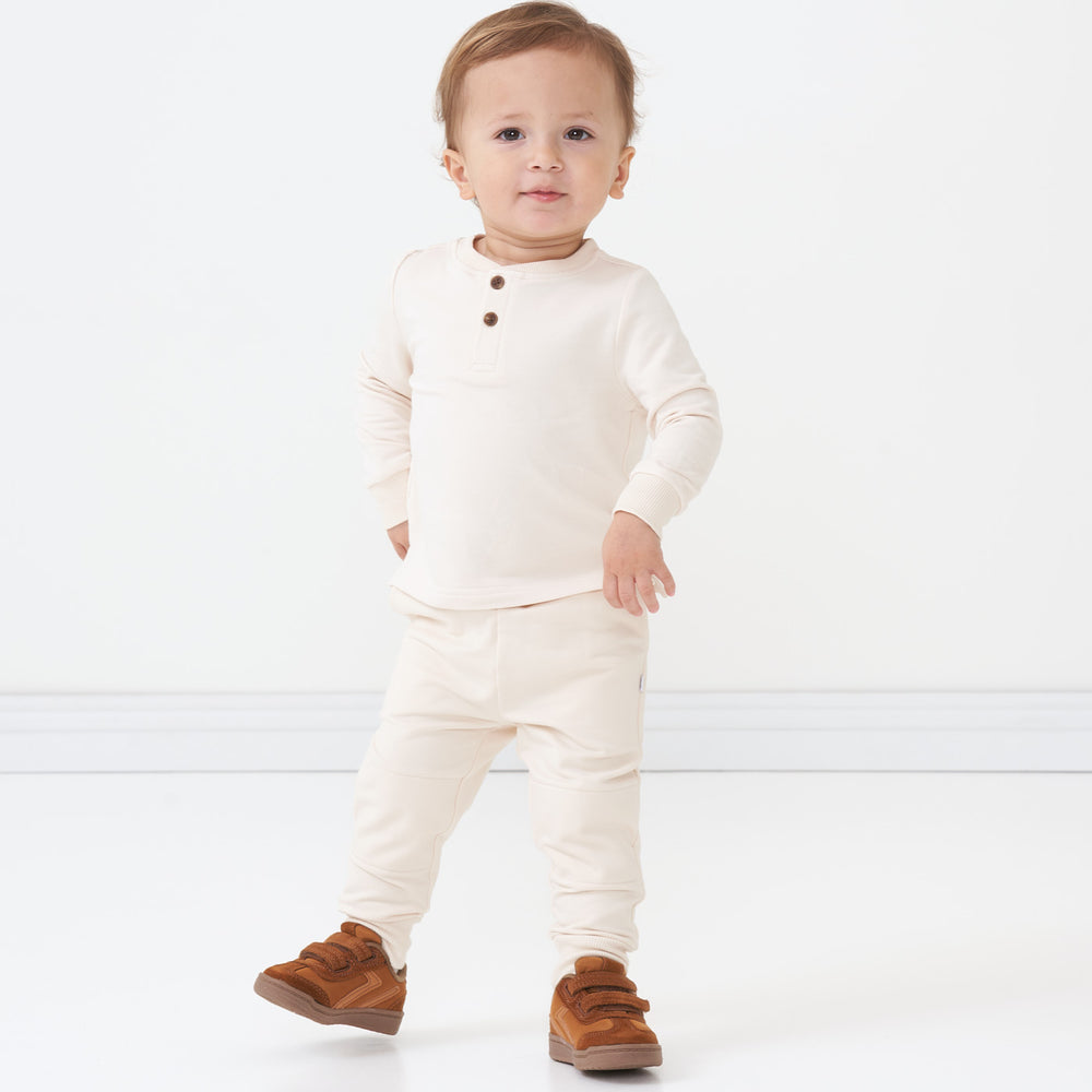 Child with their hands on their hips wearing a Cream henley tee and matching joggers