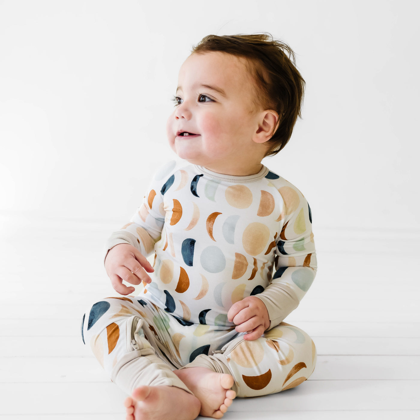 Child sitting wearing a Luna Neutral crescent zippy