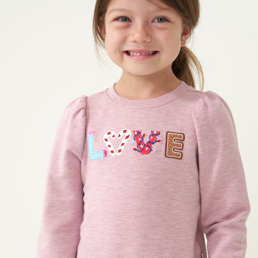 Close up image of a child wearing a Heather Mauve Love puff sleeve crewneck