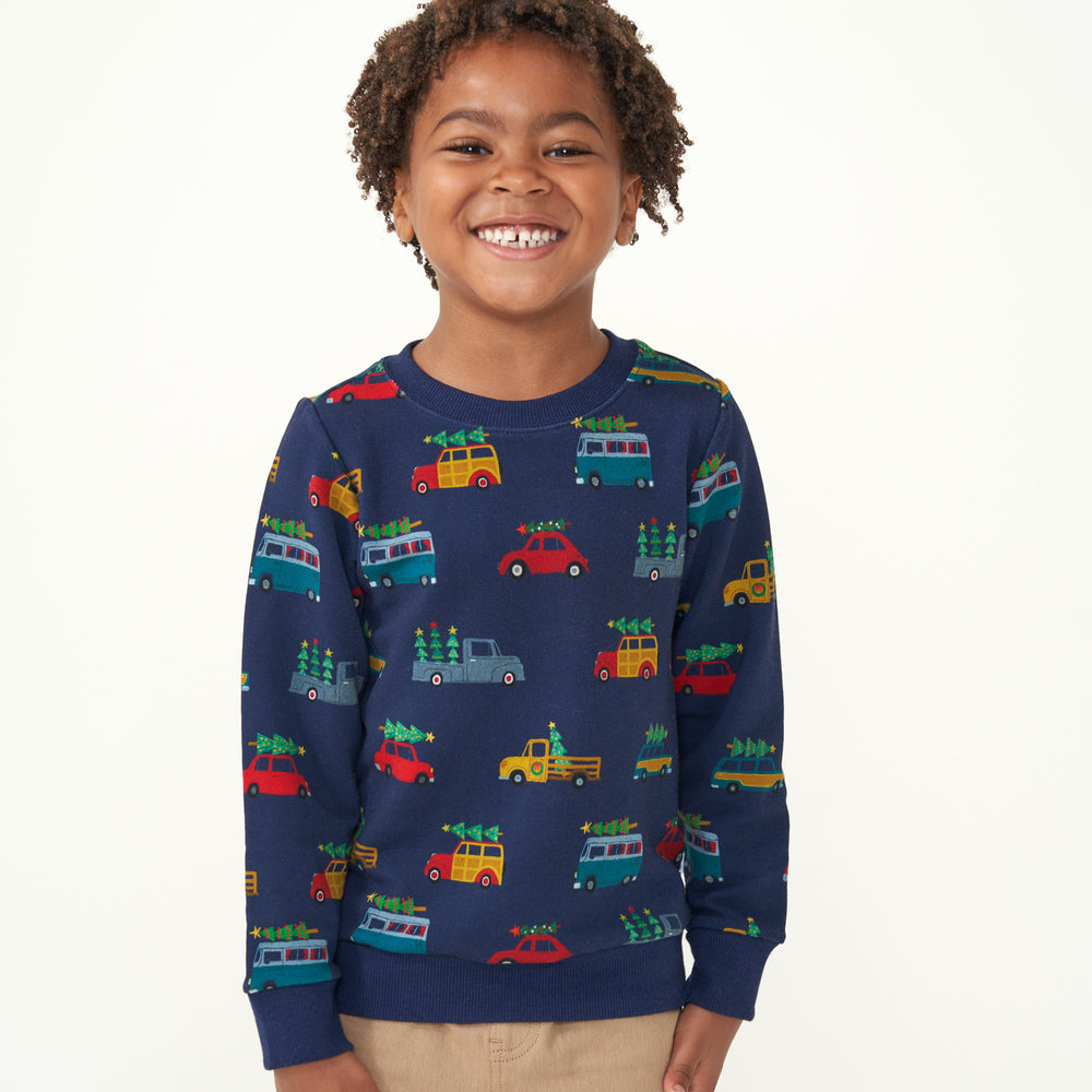 Child with their arms at their sides wearing a Tree Traffic crewneck sweatshirt