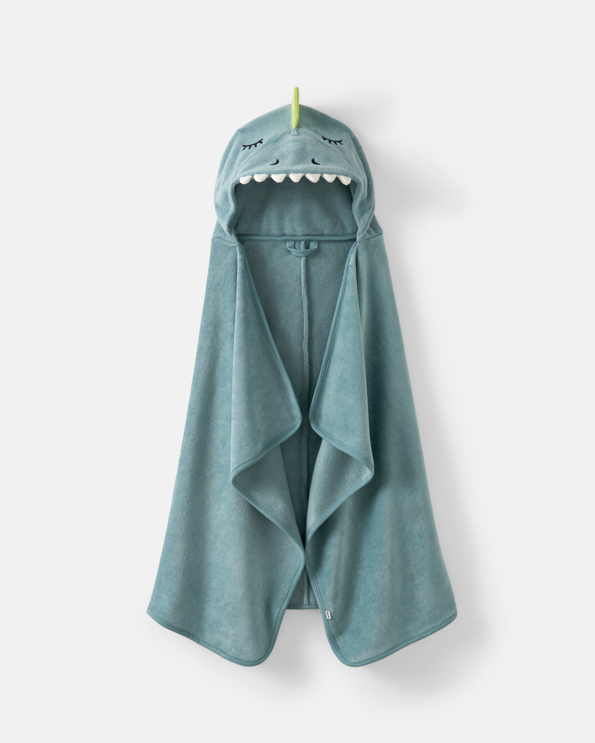 A teal blue hooded towel with a dino face design on the hood, featuring embroidered eyes, nose, and white teeth, hanging against a light gray background.