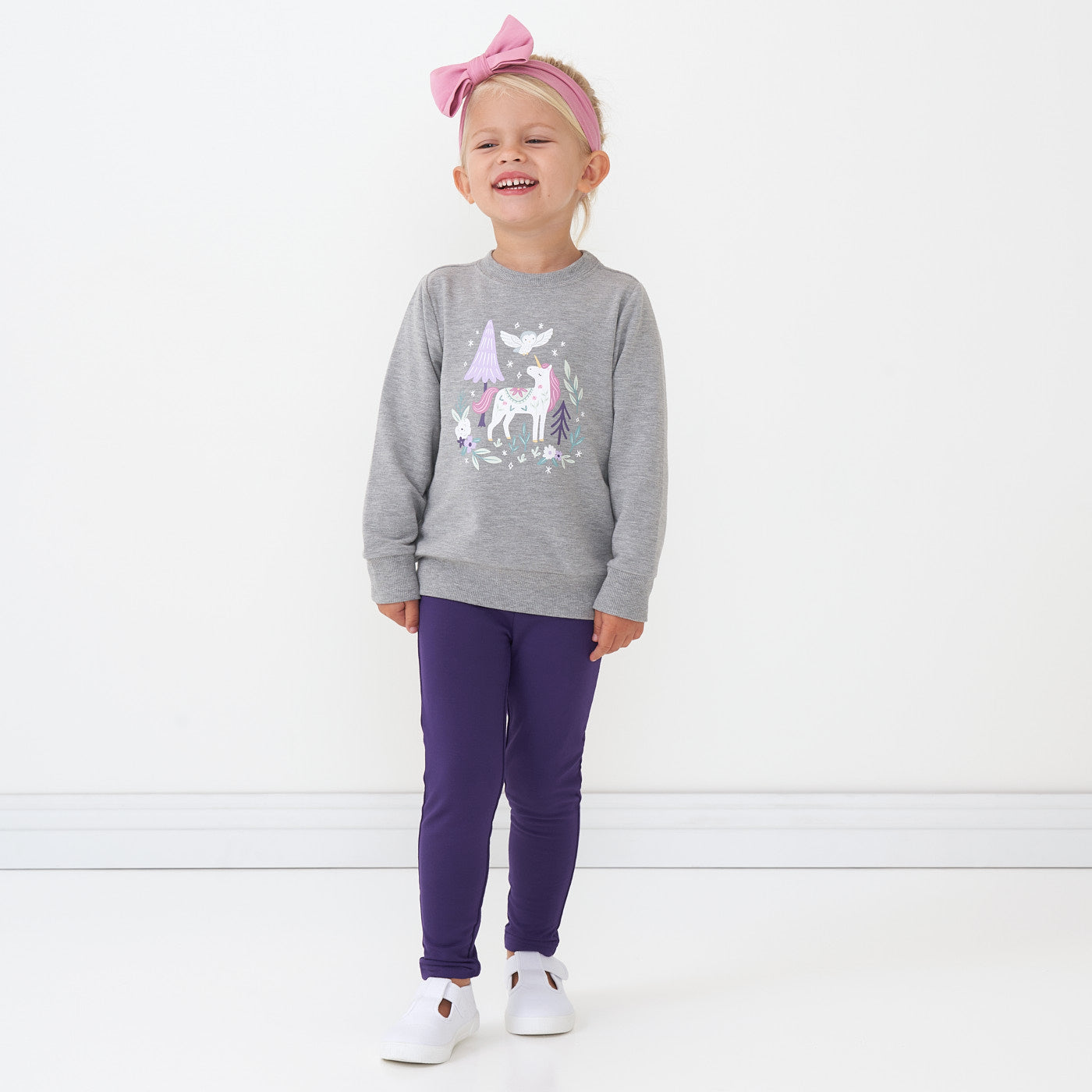 Child wearing Deep Amethyst cozy leggings and coordinating crewneck sweater and luxe bow headband